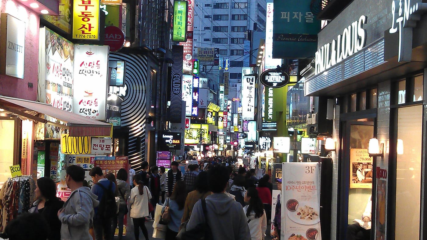 Evening crowds and storefront signs along a Myeongdong street