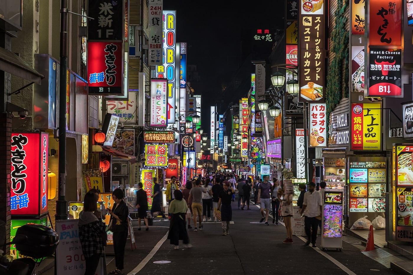 A Kabukicho street in Shinjuku lined with illuminated neon signs at night