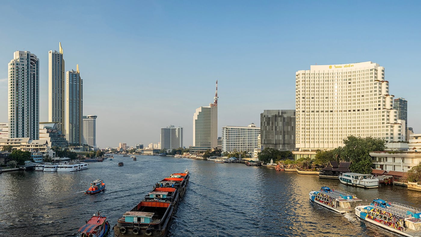 Boats on the Chao Phraya River and Bang Rak's riverside buildings, looking north from Taksin Bridge