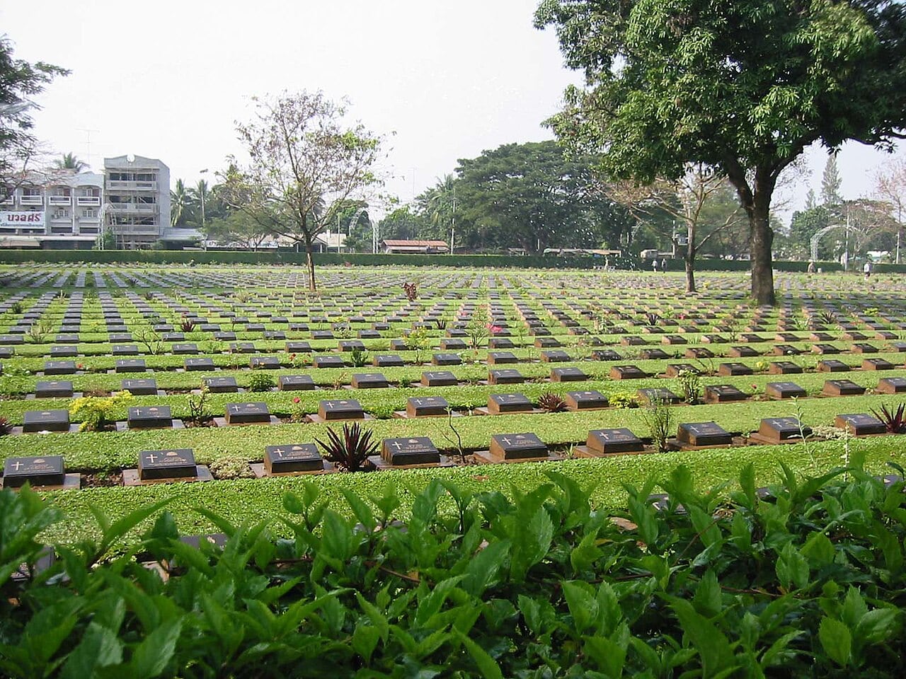 Rows of headstones across the maintained lawns of Kanchanaburi War Cemetery
