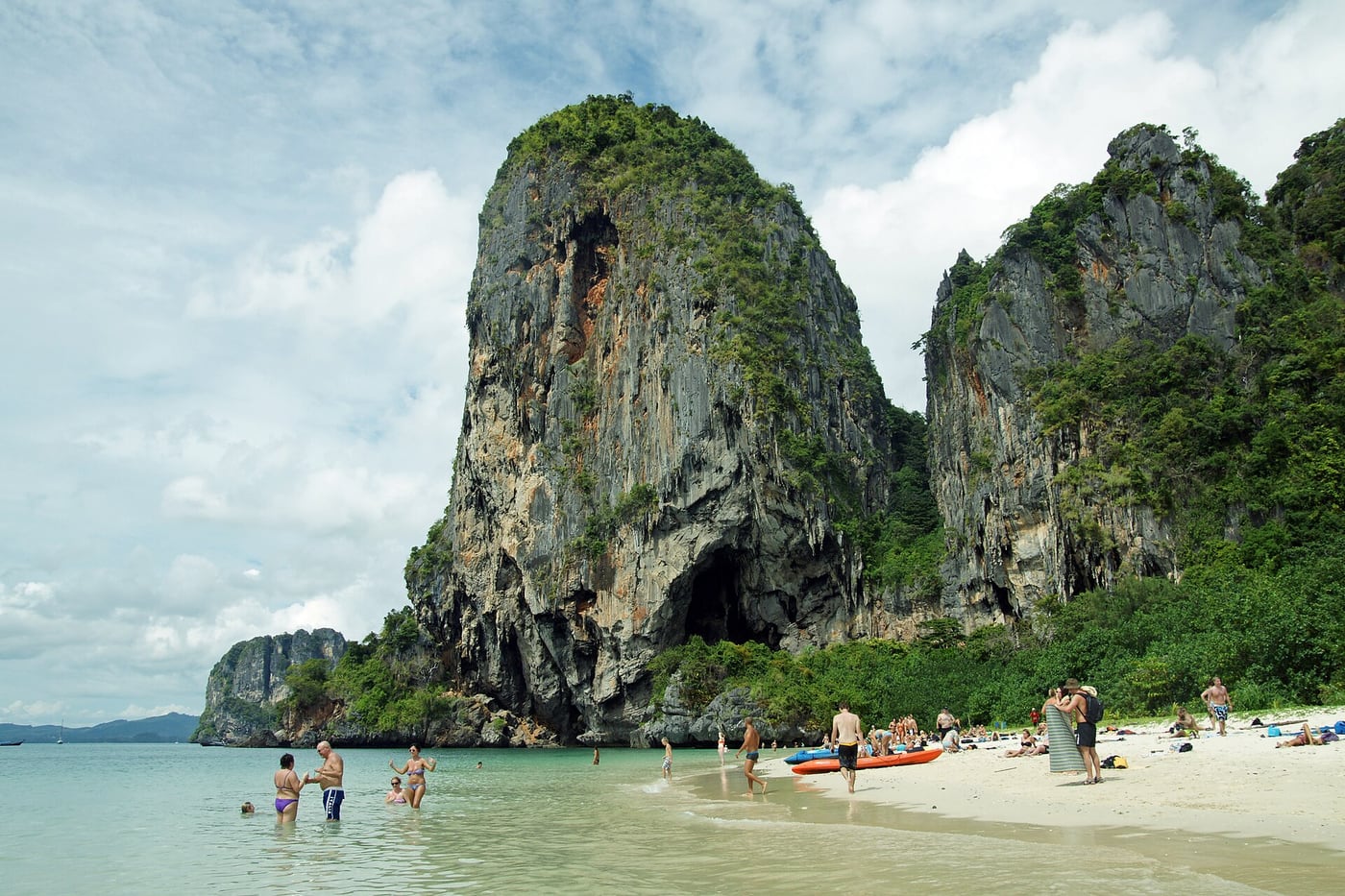 Sand, shallow water and visitors beneath the limestone cliffs at Phra Nang Beach