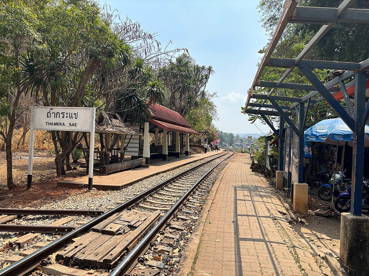 The sign, platform and curving track at Tham Krasae station, illustrating a location along the railway route