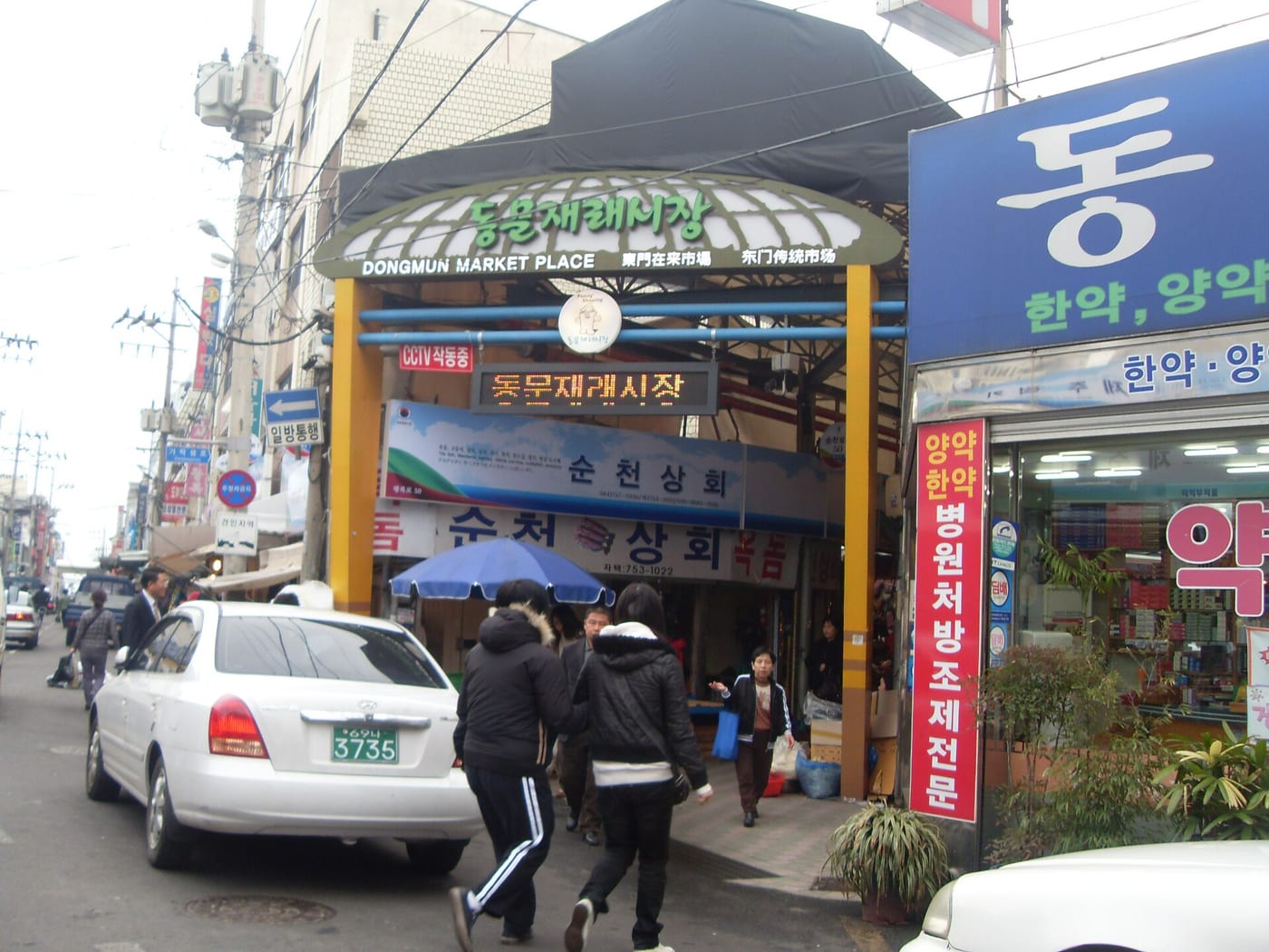 간판 아래 사람들이 오가는 제주 동문재래시장 입구