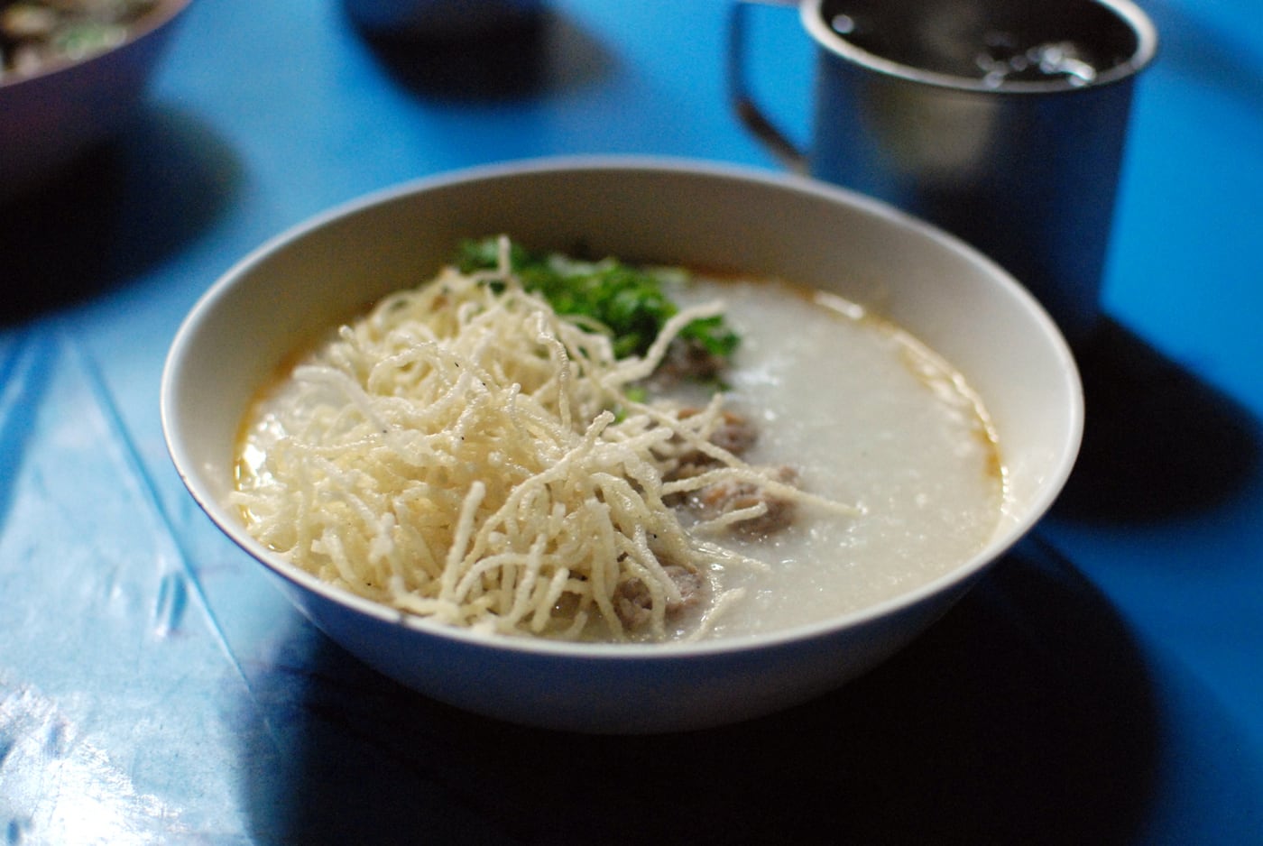 Breakfast dish reference: jok mu sap, Thai rice congee with minced pork and crisp noodles.